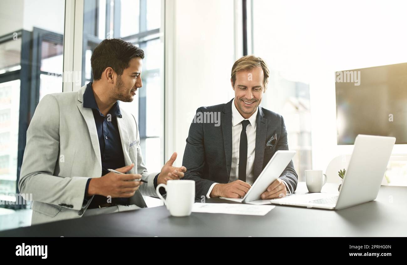 They are using technology to its true competitive advantage. two businesspeople having a discussion in an office. Stock Photo