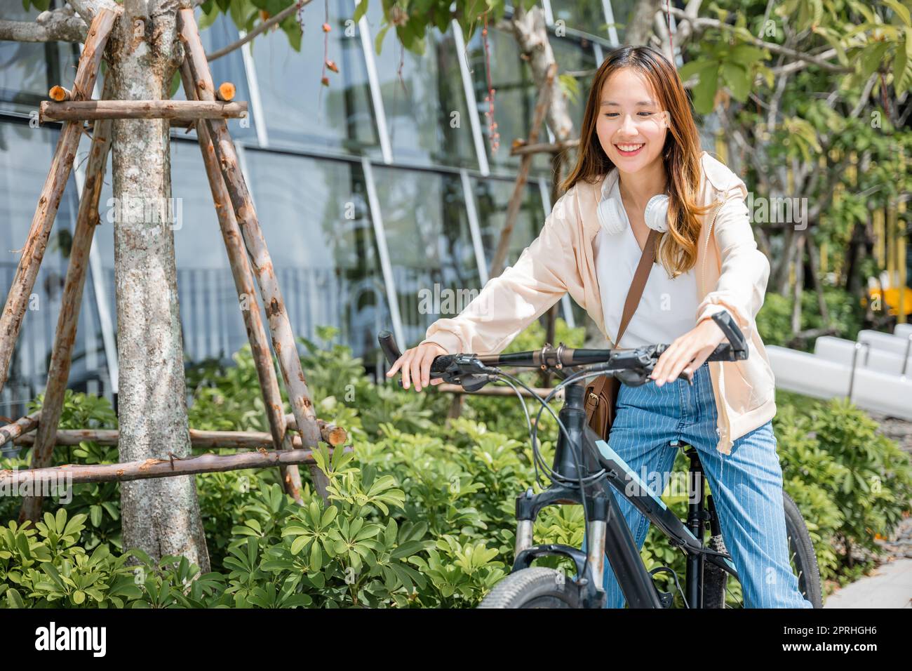 Happy Asian beautiful young woman riding bicycle on street outdoor near building city Stock Photo