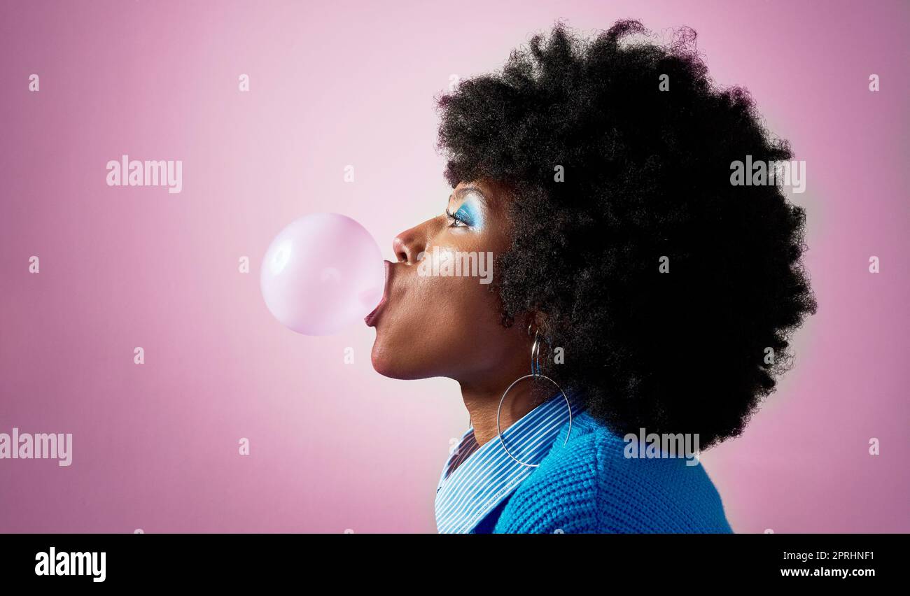 Bubble gum, afro hair and black woman on pink studio background with