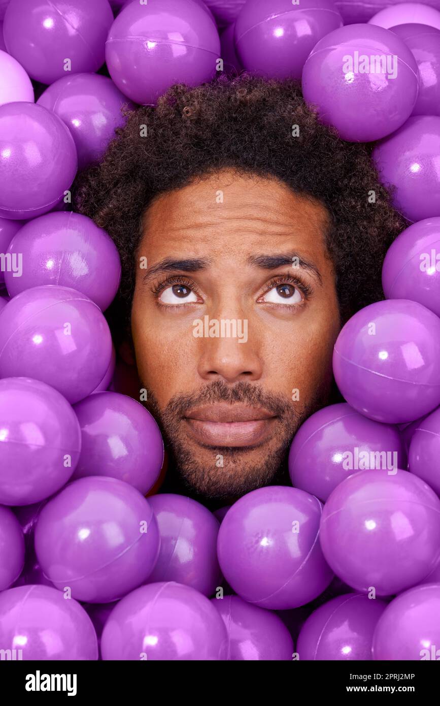 Hmmm.....A young black mans face amongst purple pit balls Stock Photo