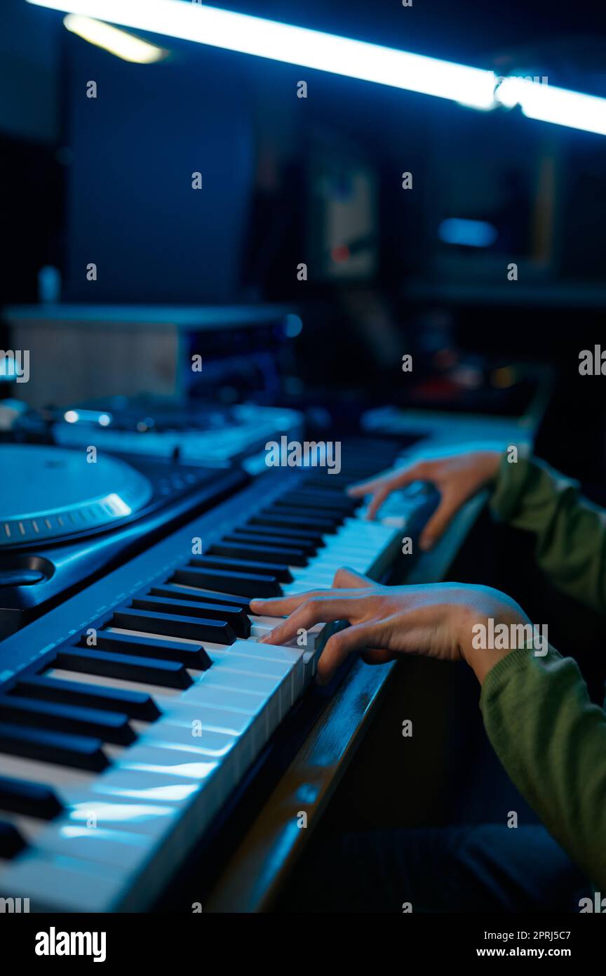 Young keyboardist musician artist playing on synthesizer in neon light