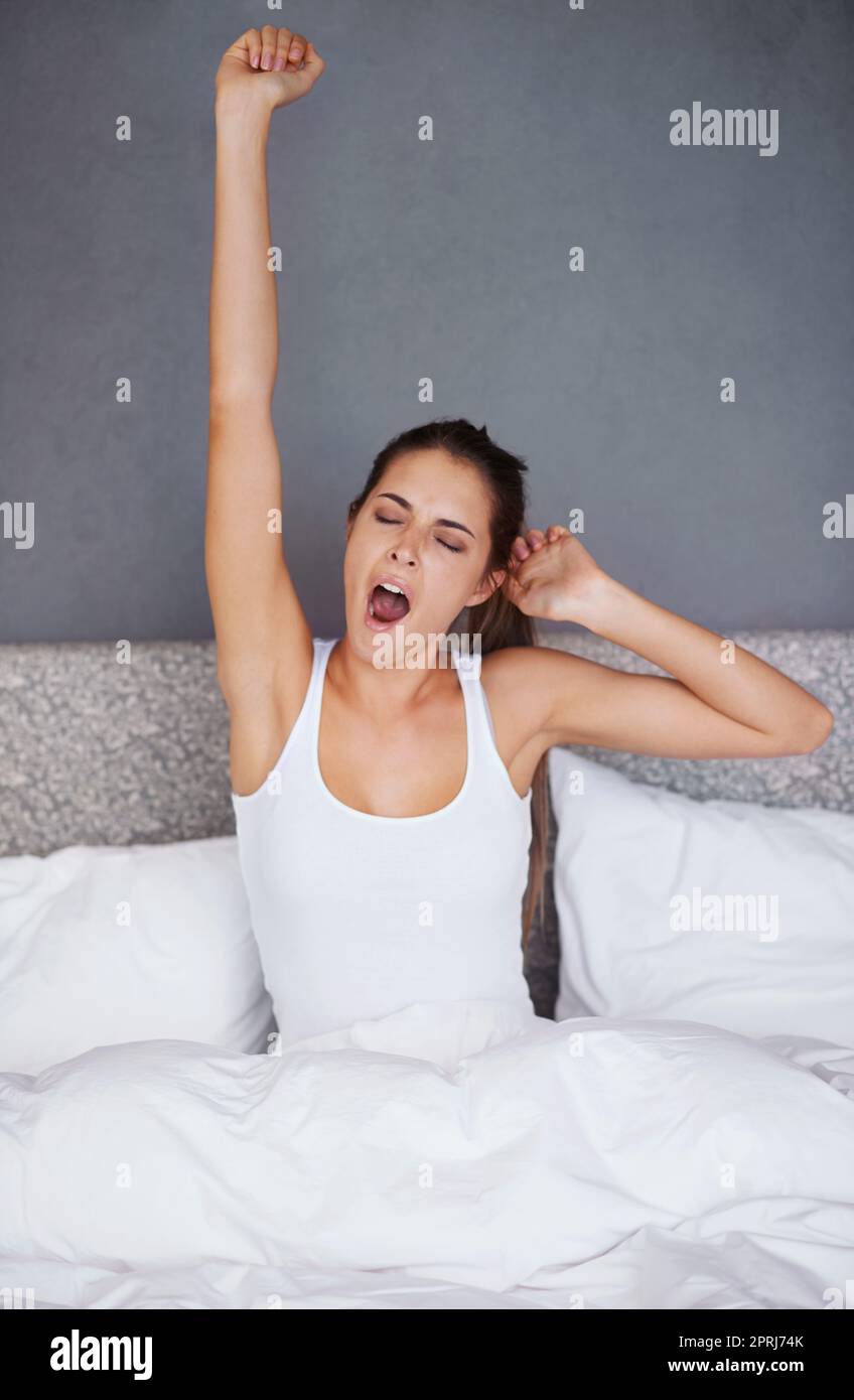 Do I really have to wake up now. a young woman stretching her arms and