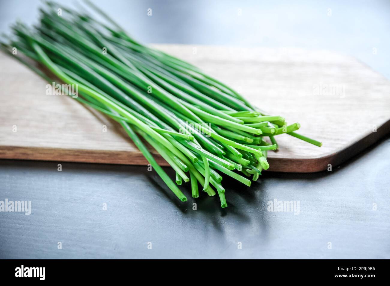 Bunch of chives on a wooden cutting board Stock Photo