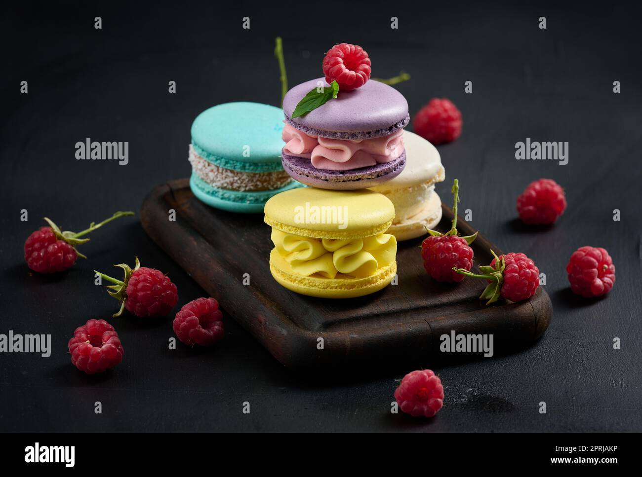 A stack of multi-colored macaroons on a wooden board. Stock Photo