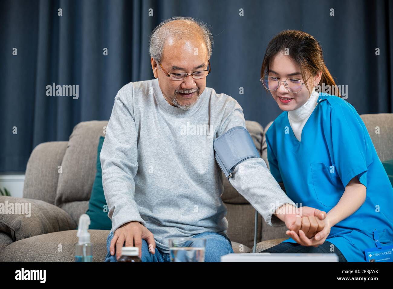 Asian doctor woman examine do checking old man client heart rate with pulsimeter monitor Stock Photo