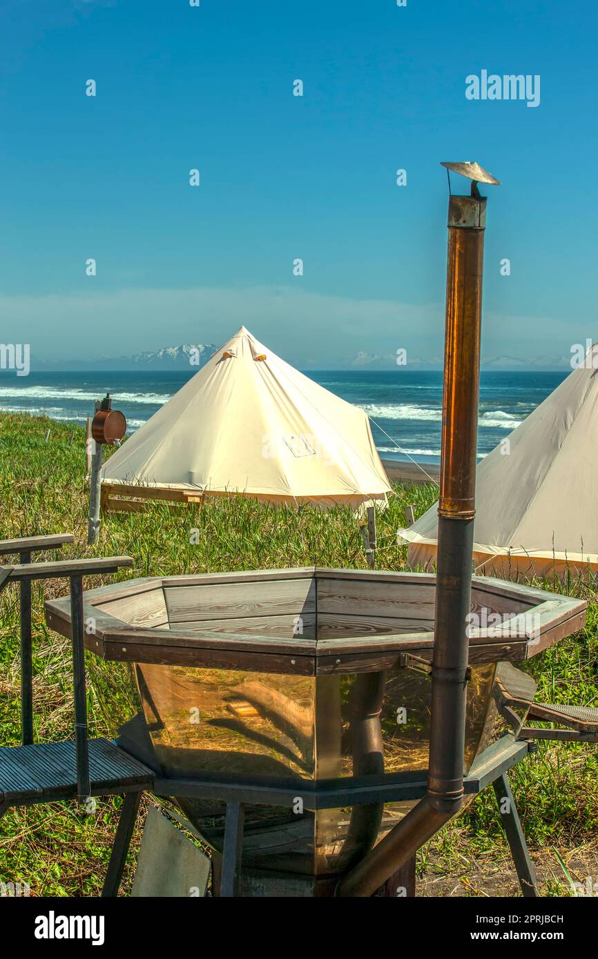 Glamping house and outdoor bath tub on ocean coast, rural landscape