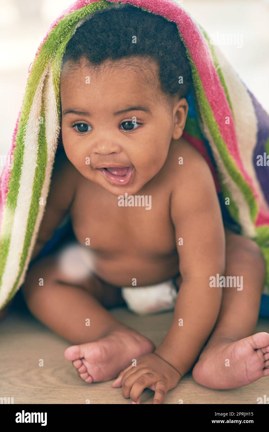 Sweet bundle of joy. an adorable baby girl covered in a colorful blanket at home. Stock Photo