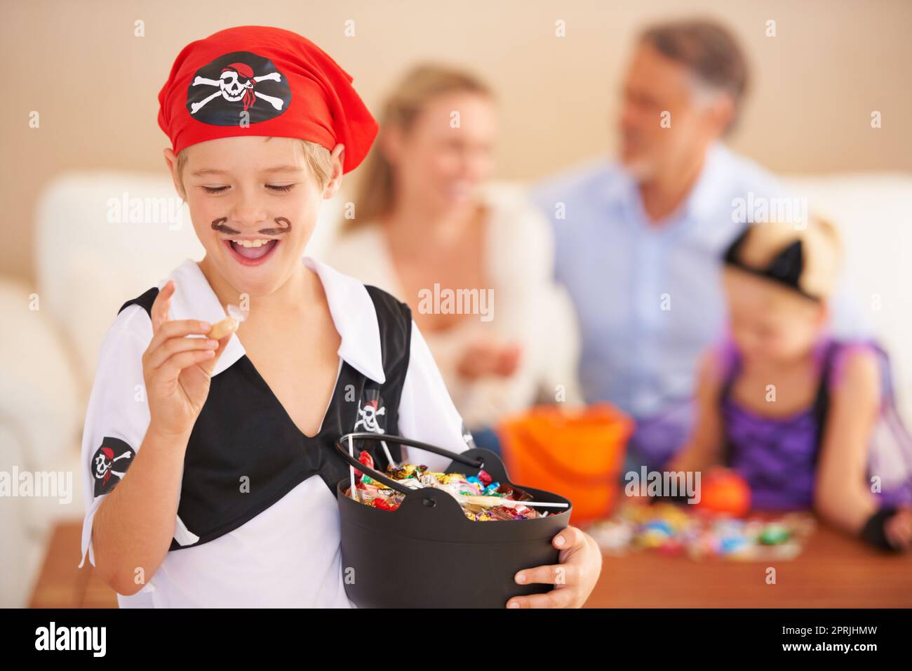 His favorite kind. A little boy dressed in a pirate costume and holding a  basket and expressing excitement about a sweet with family sitting in the  ba Stock Photo - Alamy