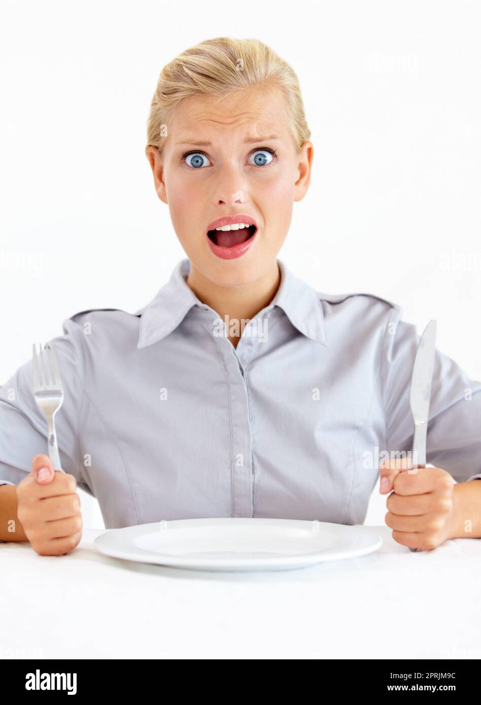 Wheres my food. Dismayed young woman sitting in front of an empty plate