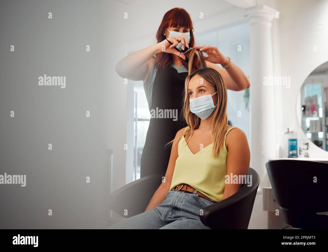 Covid, mask and hairdresser women in salon with protection for professional hair grooming business. Los Angeles hairstylist busy cutting with medical Stock Photo