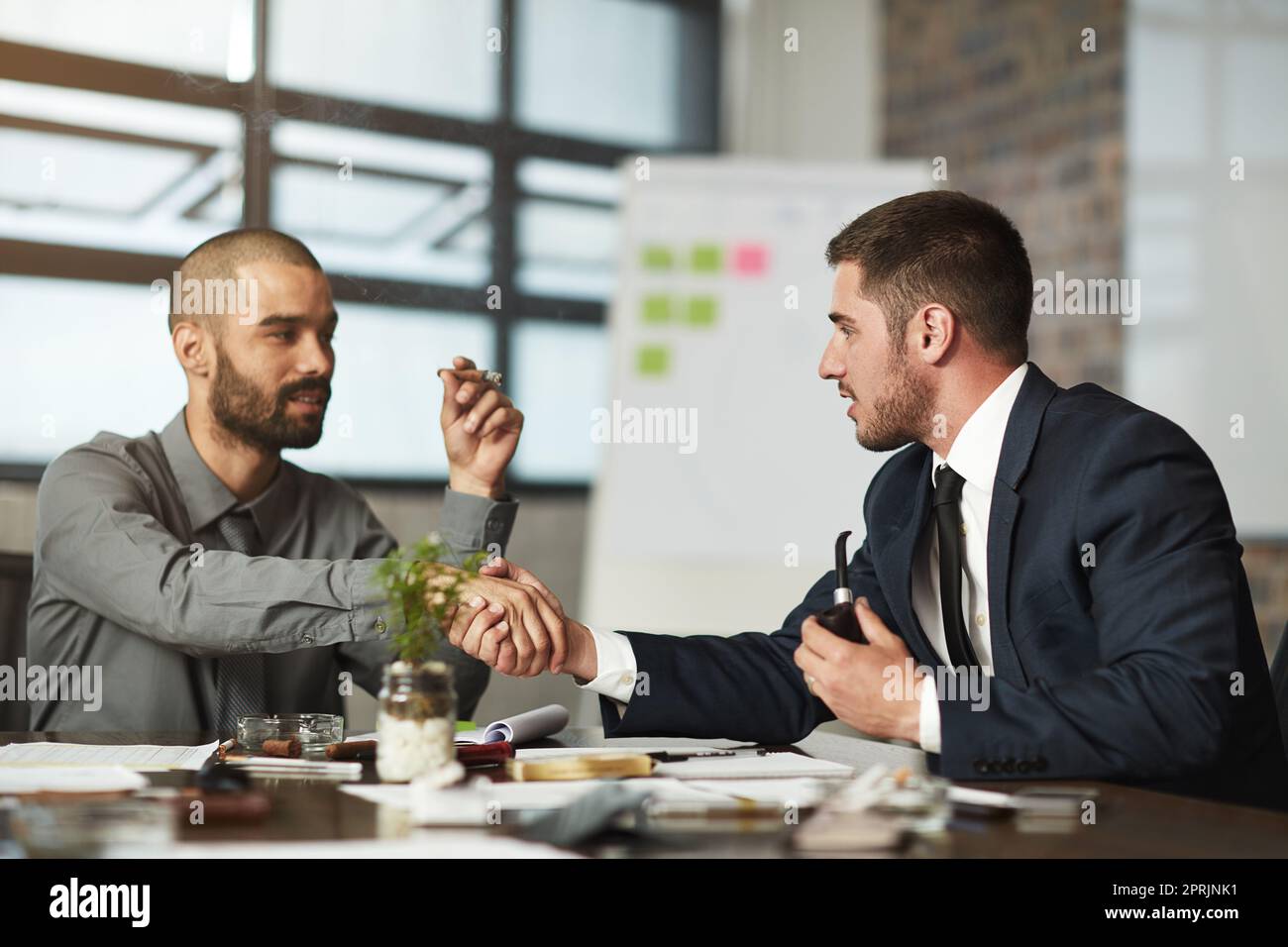 Sealing the deal over a smoke. two businessmen smoking a cigar and pipe