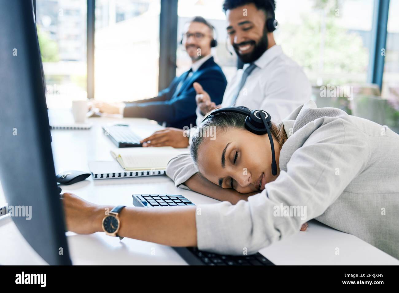 Burnout, tired and sleep at desk with call center employee at desk in customer service, ecommerce or telemarketing company. Business woman, exhausted and overworked customer support agent in office Stock Photo