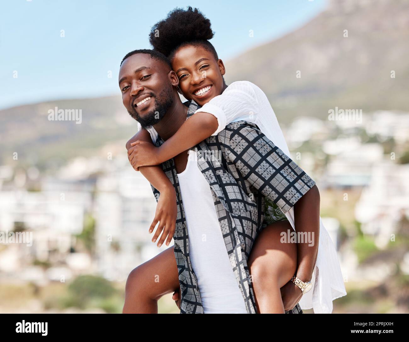 Portrait, black couple and back ride with a smile in nature outdoors on a date, trip or vacation. Love, romance and happy man and woman together with male carrying female on his shoulders outside. Stock Photo