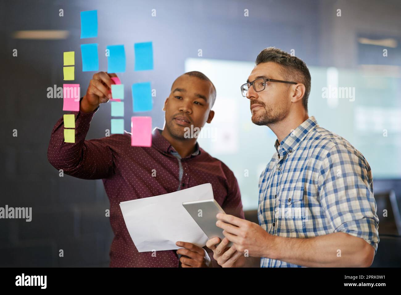 Together we can elevate our ideas towards success. two coworkers going over documents together. Stock Photo