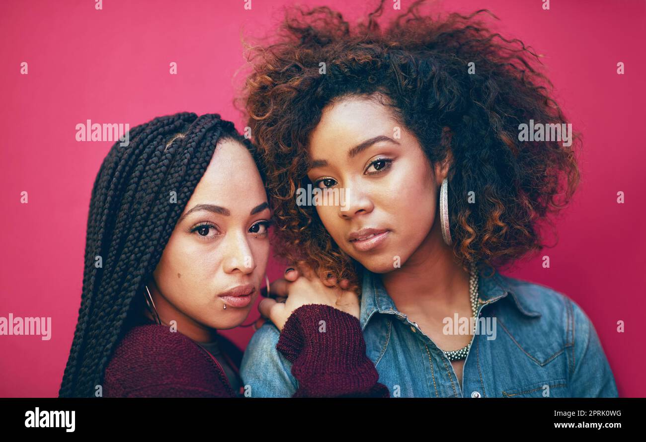 Shes my best friend. Break her, Ill break your face. Portrait of two girlfriends posing against a pink background. Stock Photo