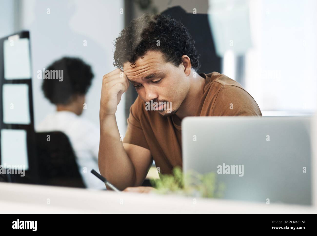 This makes no sense. a handsome young businessman sitting in the office and feeling stressed while using his cellphone Stock Photo