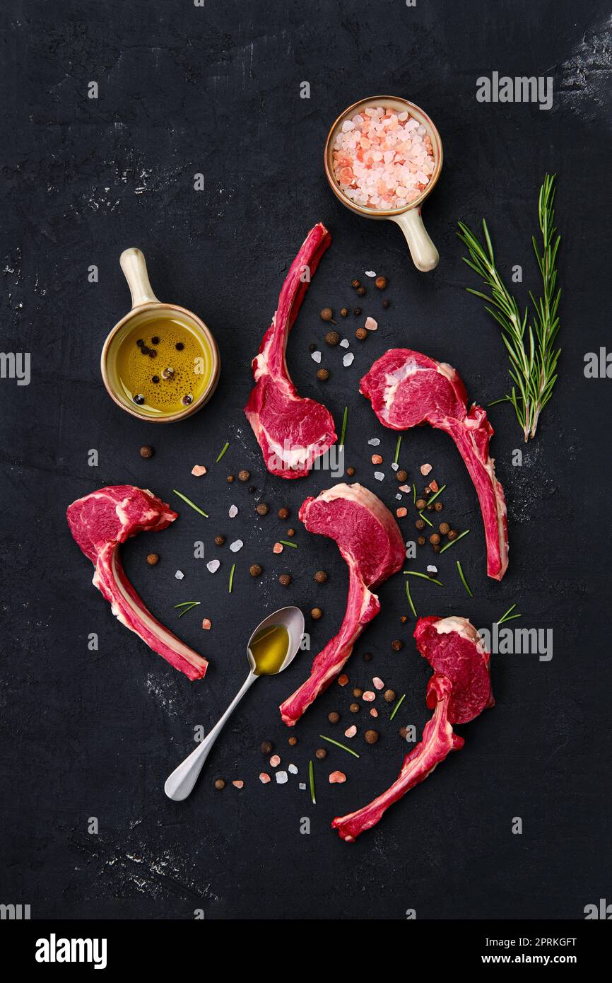 Composition with rack of lamb, seasoning and herbs on dark background