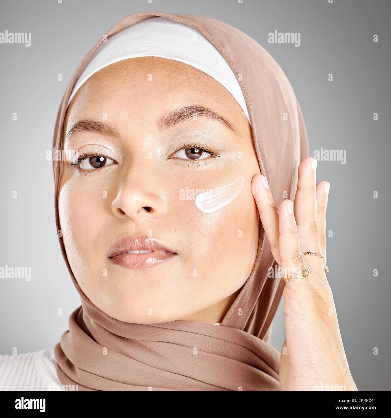 Muslim, beauty and skincare woman with cream on face product against a
