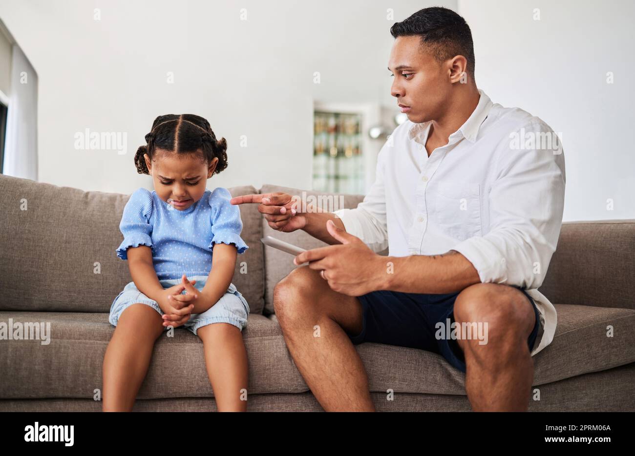 Angry, father with tablet and kid conflict, upset and serious scolding, no screen time with sad child and frustrated parent pointing. Family stress, b Stock Photo
