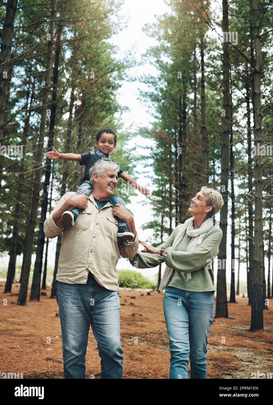 Hike, nature and children with senior foster parents and their adopted son walking on a sand path through the tress. Family, hiking and kids with an e Stock Photo