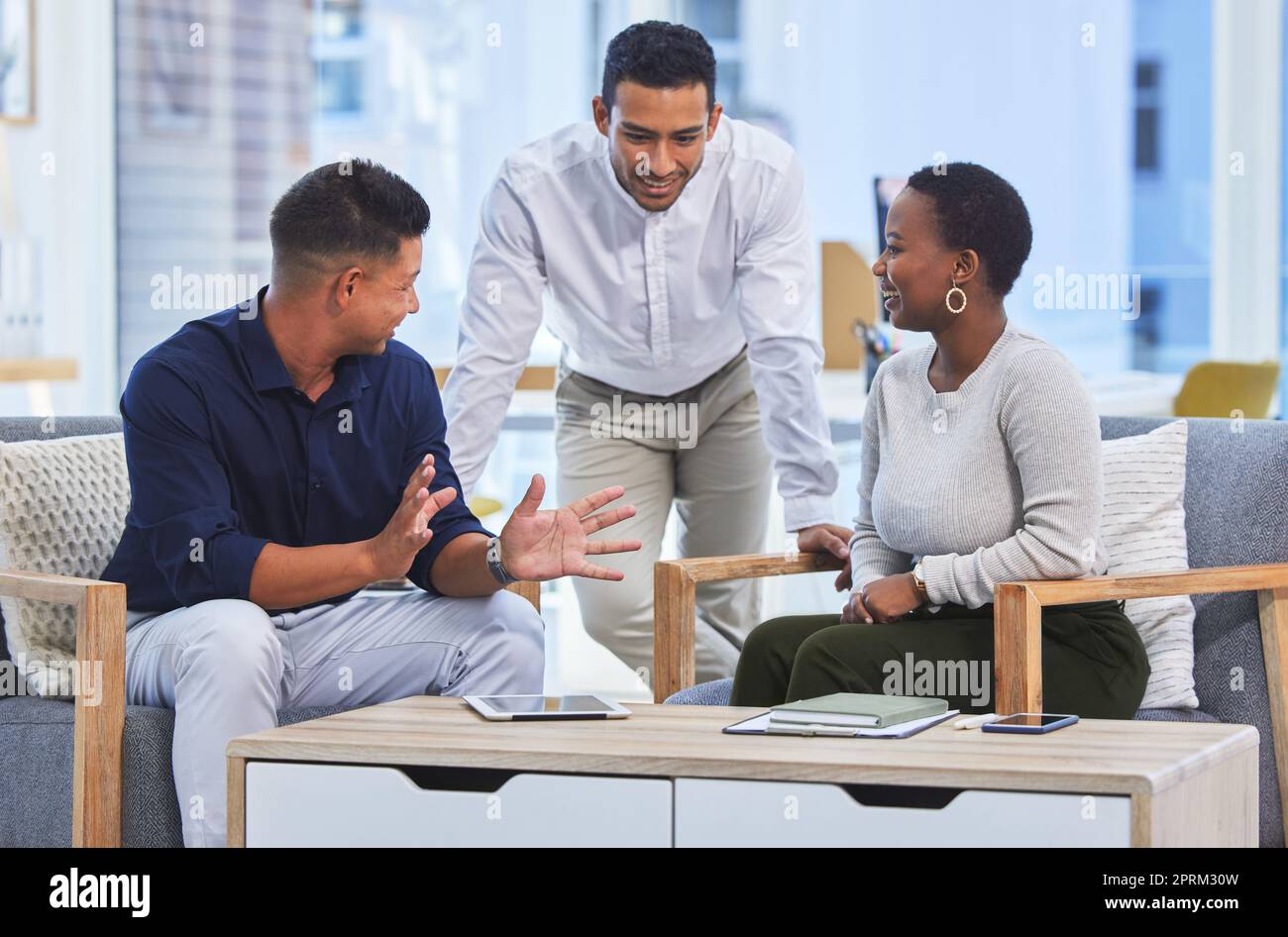 Sharing some office banter. three businesspeople having a conversation in a modern office Stock Photo