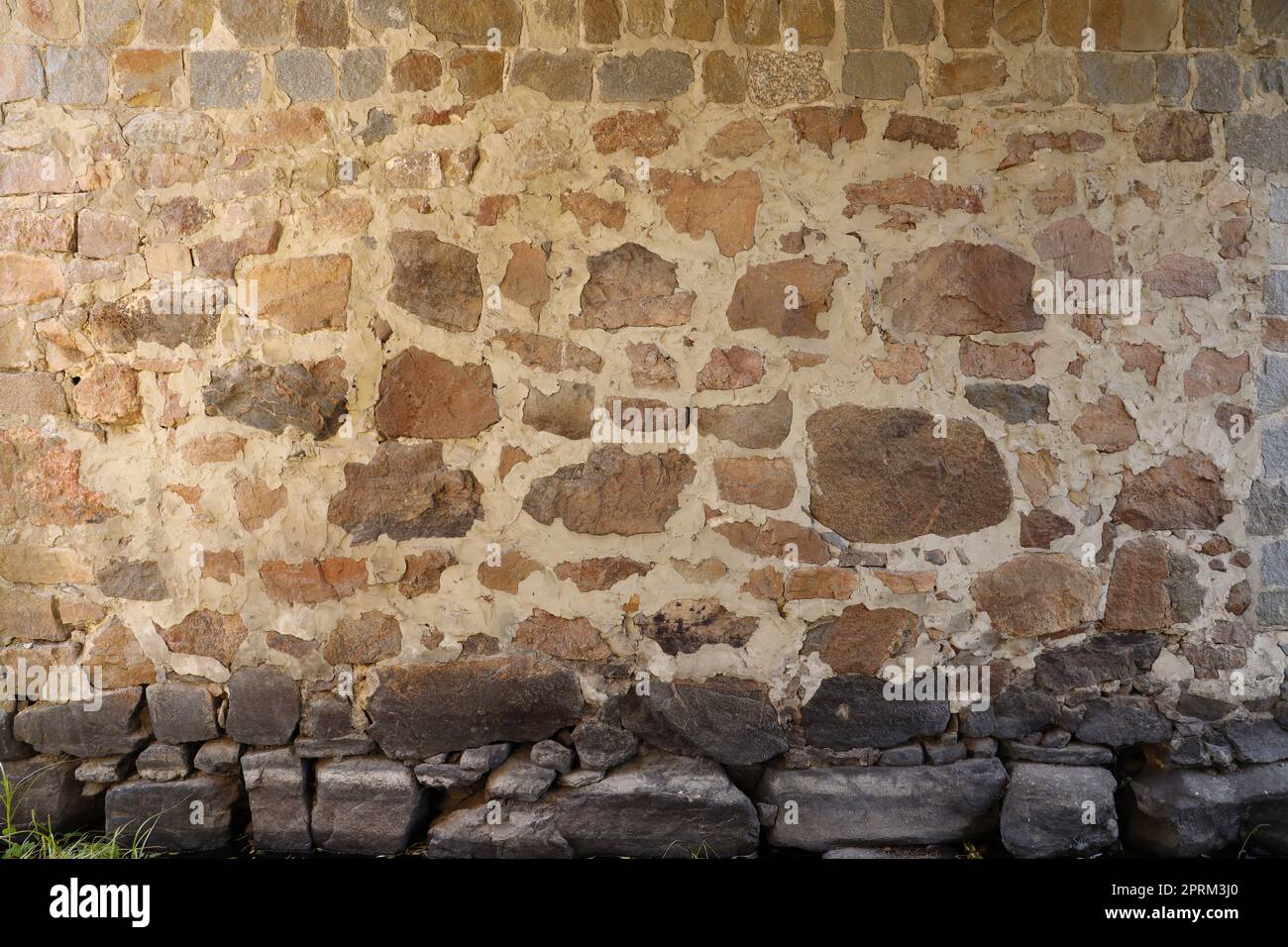 Texture of a stone wall with many big brown and grey stones armed with