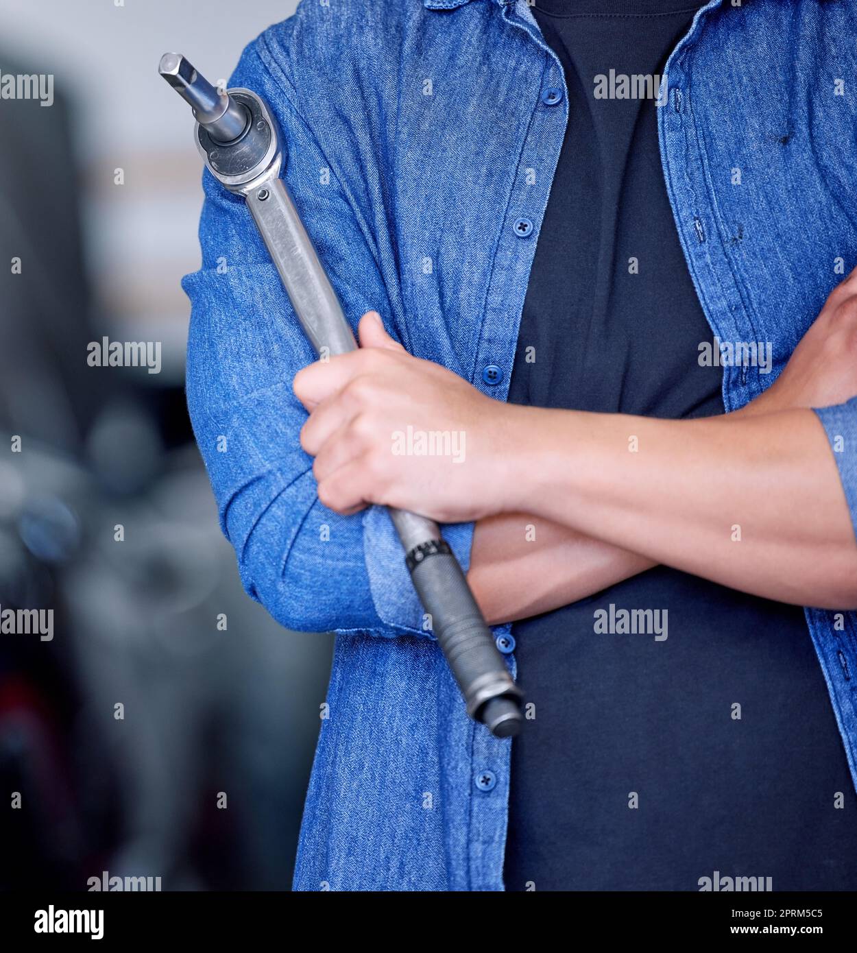 Man, hands and mechanic tool with arms crossed for vehicle repairs, assistance and engineering at garage. Professional hand of male mechanical enginee Stock Photo