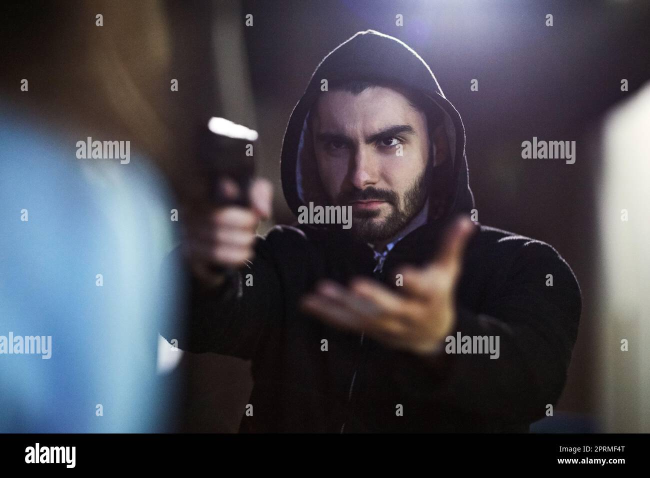 Your money or your life. a gun-wielding thief threatening an unrecognizable victim. Stock Photo