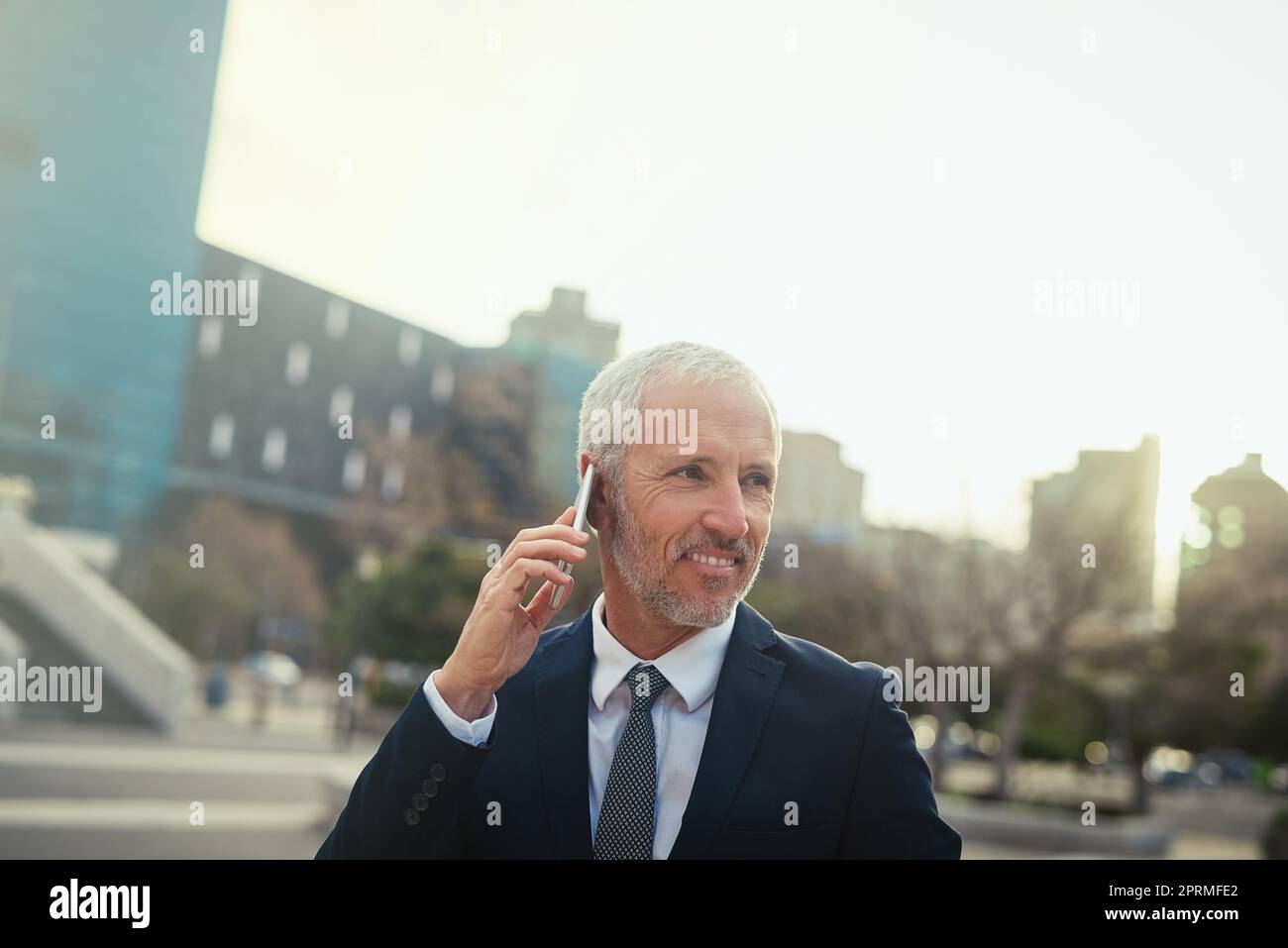 Anytime, anywhere. a businessman answering his phone while walking to his office in the city. Stock Photo