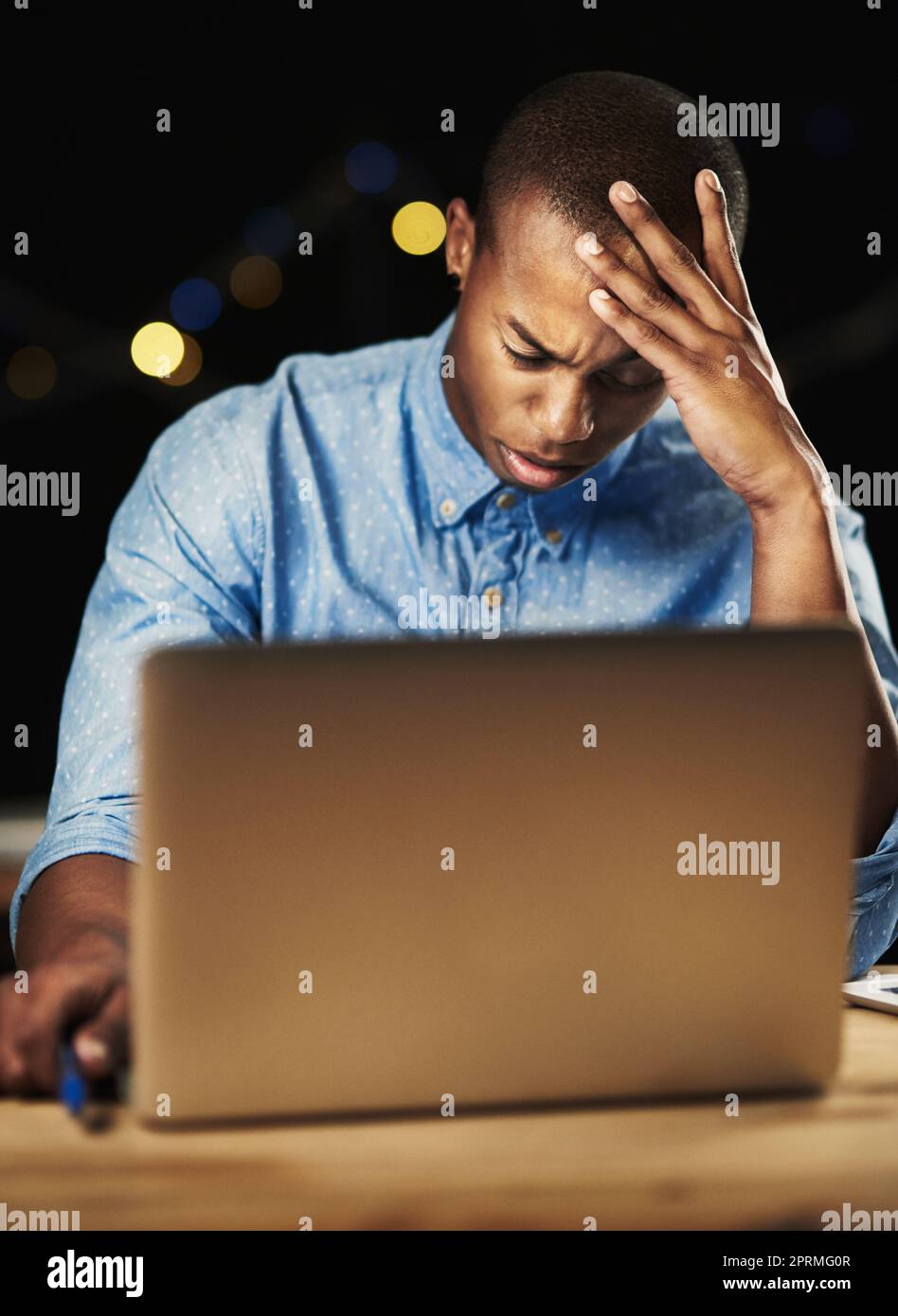 Running out of time. a young man looking stressed while working late night on his laptop. Stock Photo