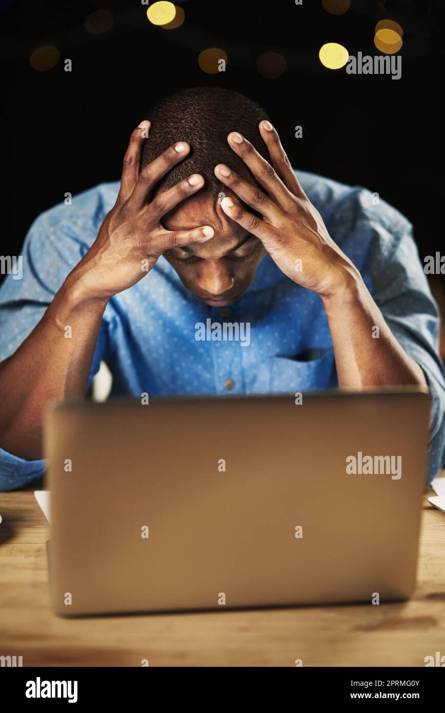 The pressure is real. a young man looking stressed while working late night on his laptop. Stock Photo