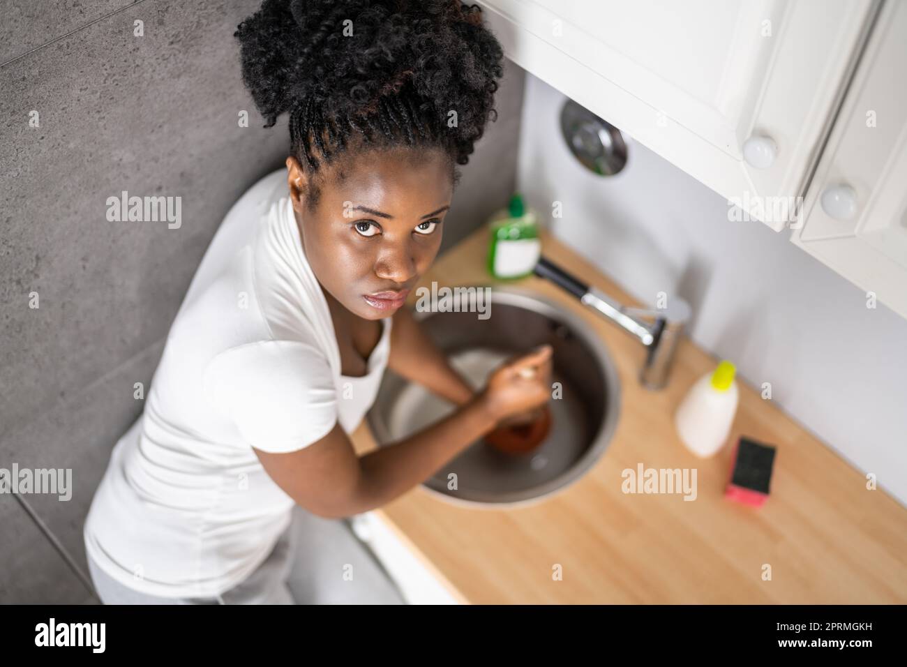 Cleaning Blocked Sink And Drain In Kitchen Using Plunger Stock Photo