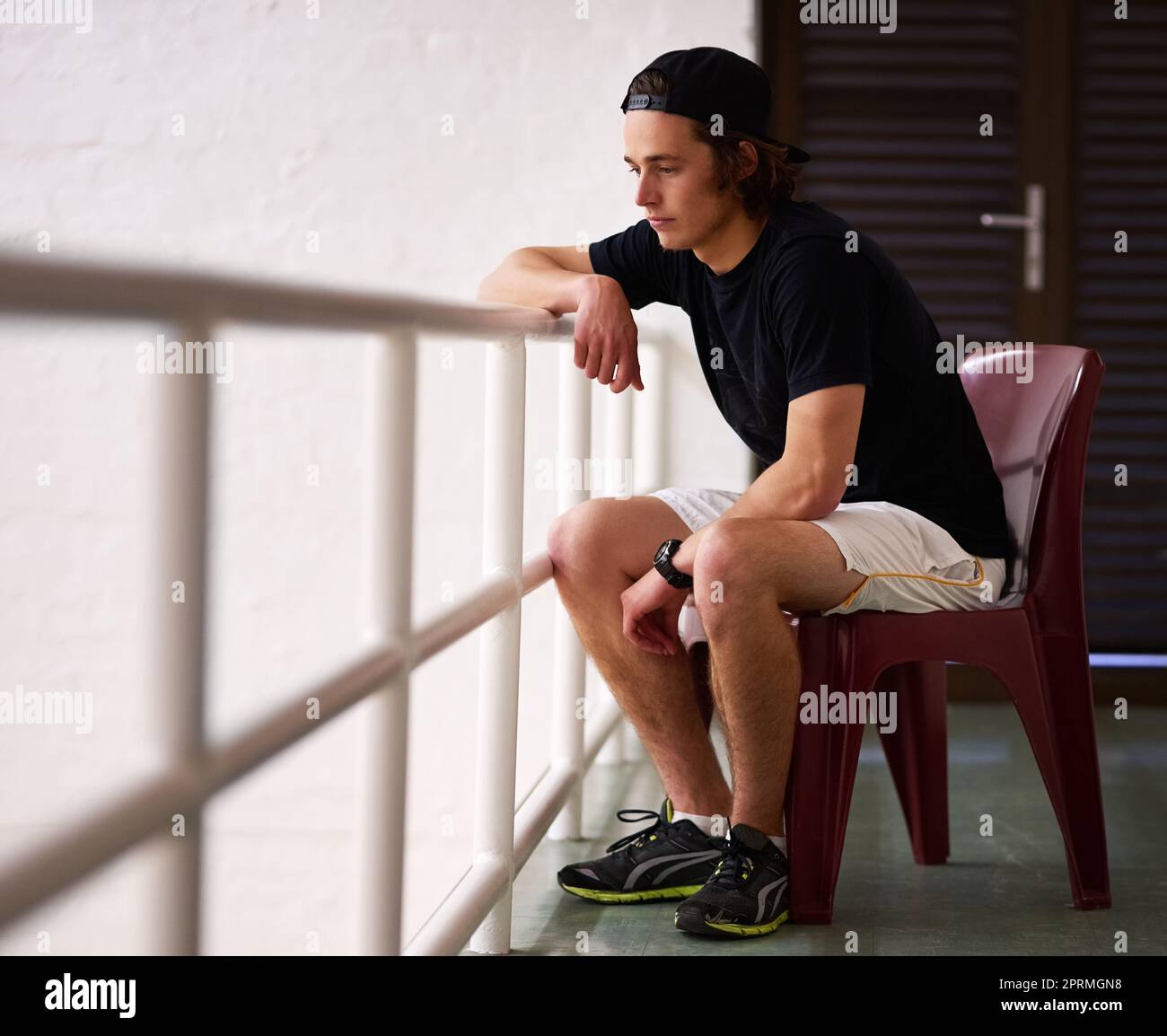 Just a spectator today. a handsome young man watching a game of squash. Stock Photo