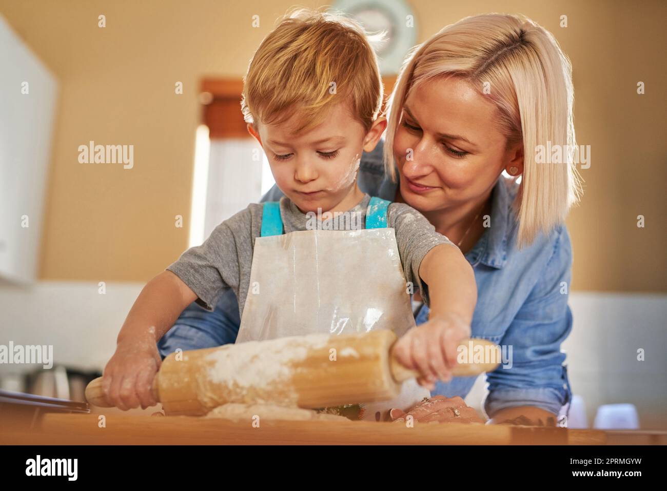 Thats it, roll the dough out gently now. a mother and son baking together at home. Stock Photo