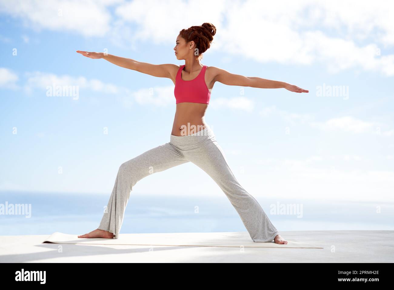 Staying balanced physically and mentally. a young woman practicing yoga outside on a sunny day. Stock Photo