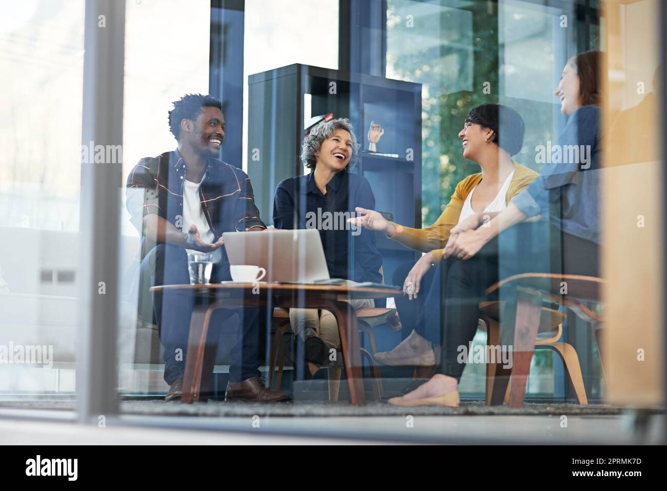 They make meetings look like fun. a team of creative businesspeople brainstorming around a laptop in the office. Stock Photo