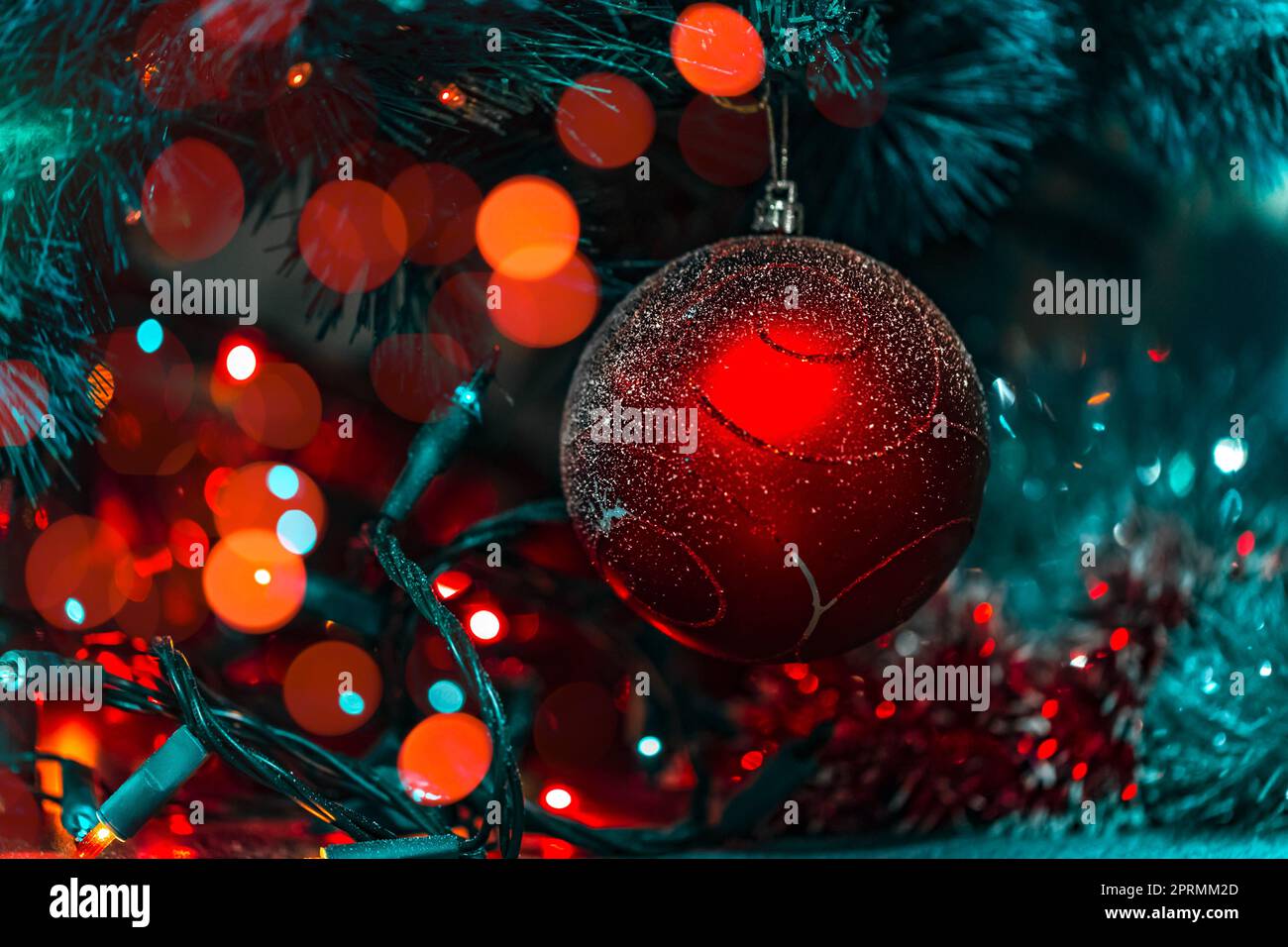 Beautiful Christmas and New Year Decorations. Holiday Background. Xmas Tree with Festive Glowing Lights and Red Shiny Ball. Stylish Baubles Ornament. Stock Photo