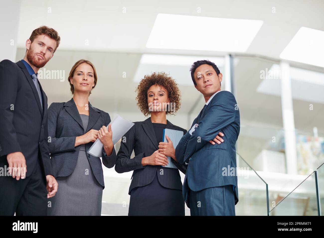 Challenges dont scare us. Portrait of a group of businesspeople standing together in a modern office. Stock Photo