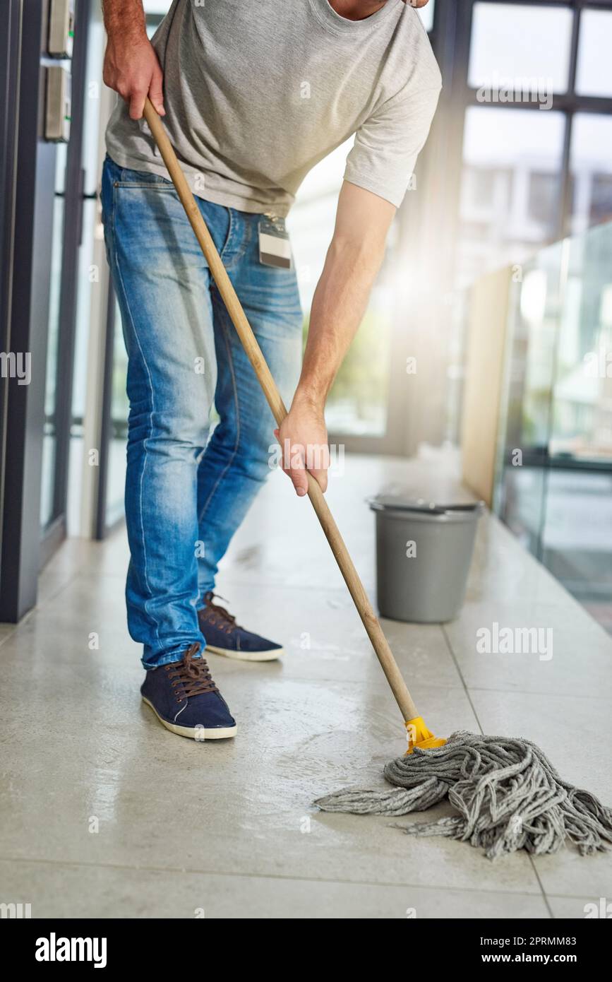 Mopping the floor. an unrecognizable man mopping the office floor. Stock Photo
