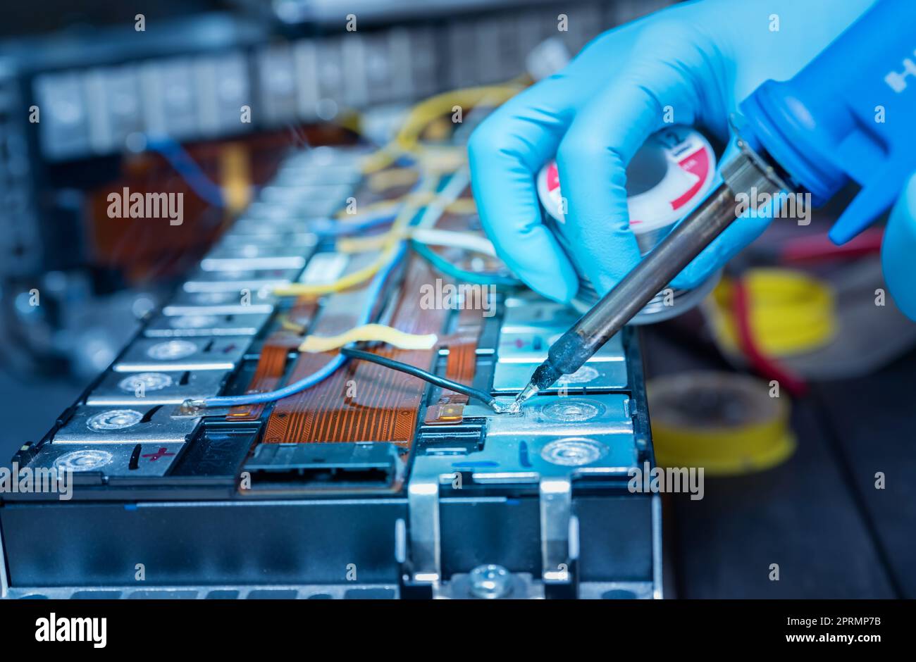 Technician use soldering iron to solder metal and wire of lithium-ion rechargeable battery. Repair module of Li-ion battery. Engineer hand holds soldering iron and tin-lead to solder electronic board. Stock Photo