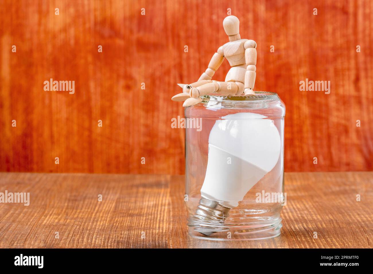 Dummy sitting on the glass jar with a lightbulb inside Stock Photo