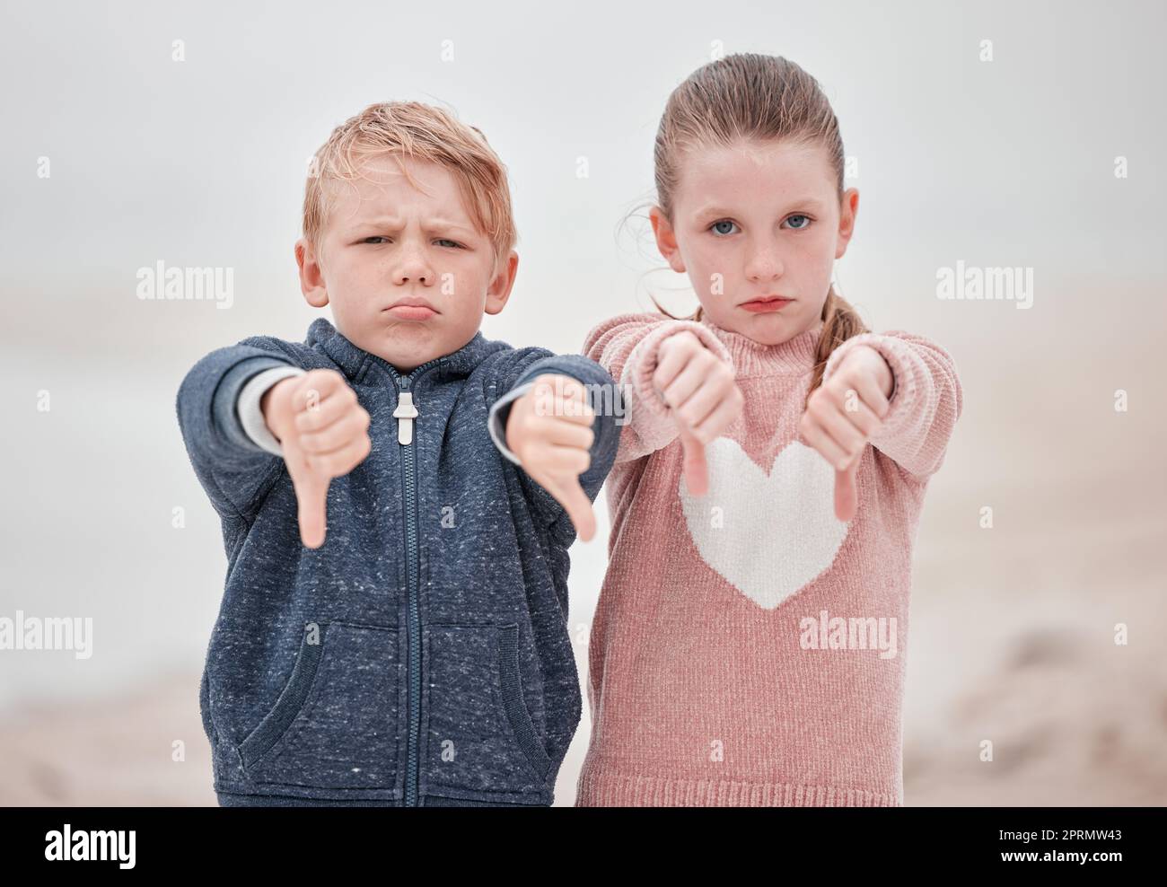 Sad children portrait, hands thumbs down or outdoor with news of negative Ukraine problem to protest war. White siblings vote no, angry emoji in cold Stock Photo