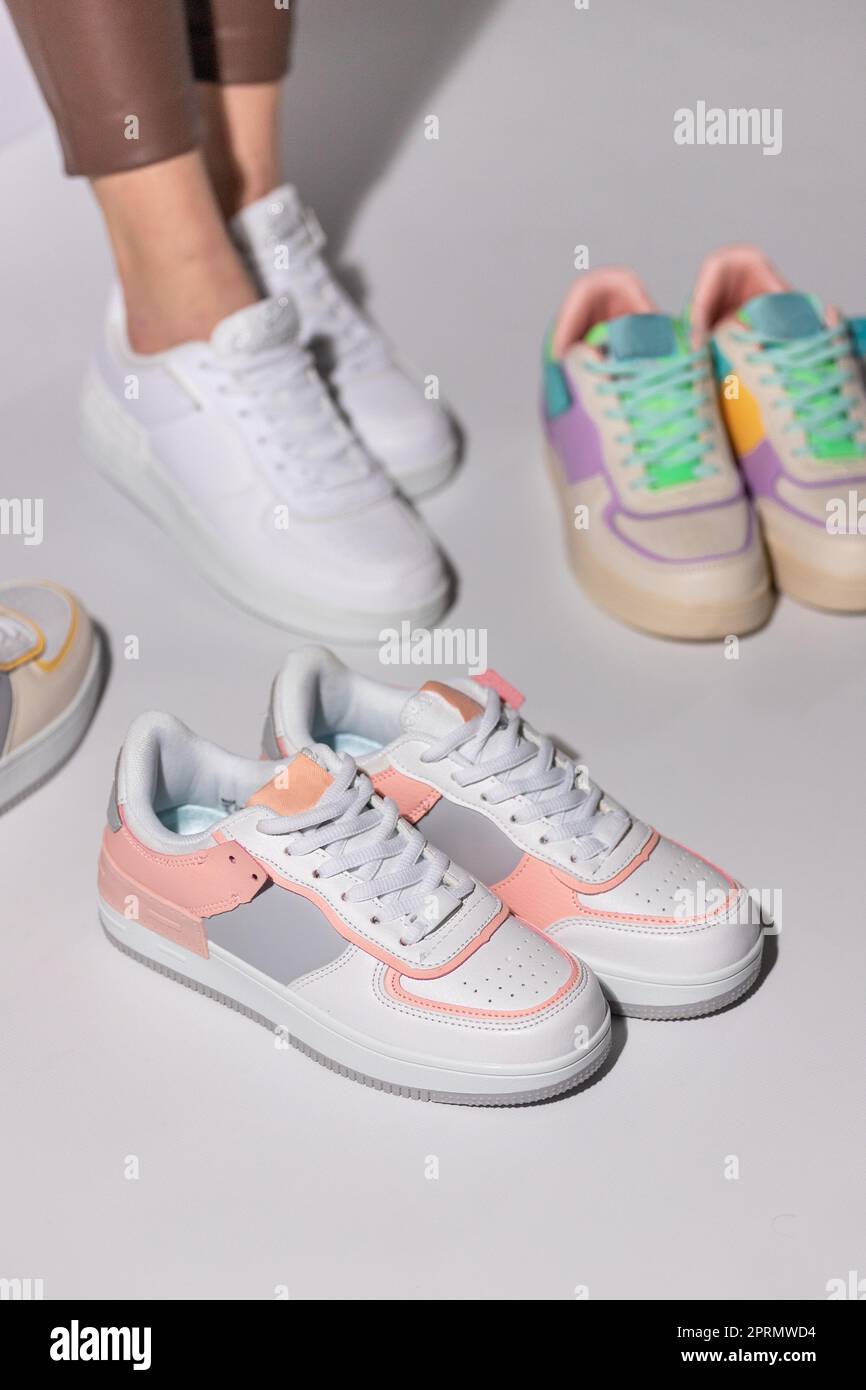 Close up of stylish white and pink women's sneakers on background of other sports shoes. Stock Photo