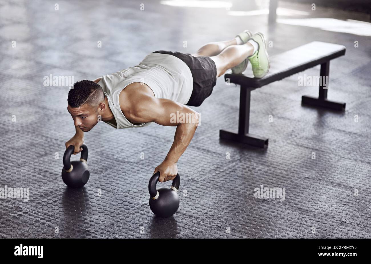 Train insane or remain the same. Full length shot of a young man working out in the gym. Stock Photo