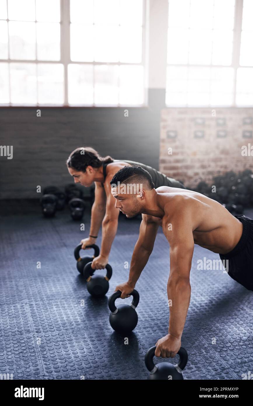 Setting up for another set. two young athletes working out in the gym. Stock Photo
