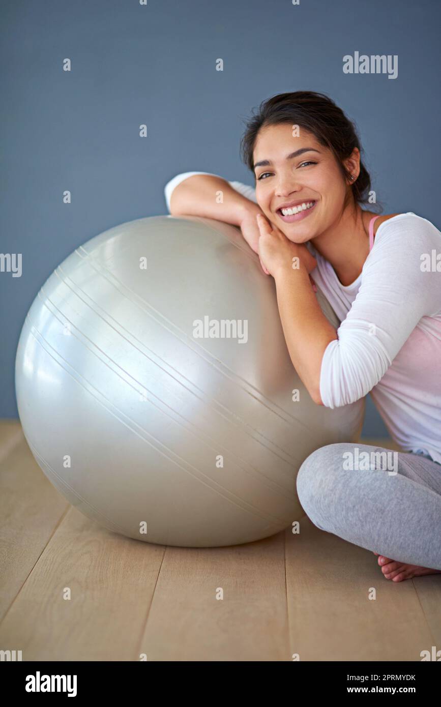 Balling my way to fitness. a sporty young woman leaning against a pilates ball. Stock Photo