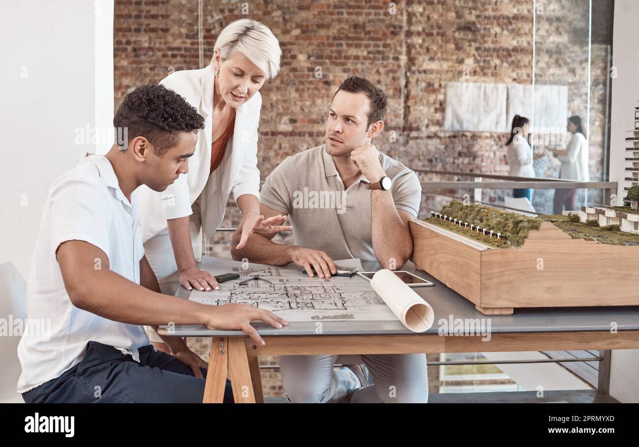 Architect, builder and engineer meeting and working as a team in an office with a blueprint and planning in the construction industry. Teamwork and collaboration on a building design or project Stock Photo