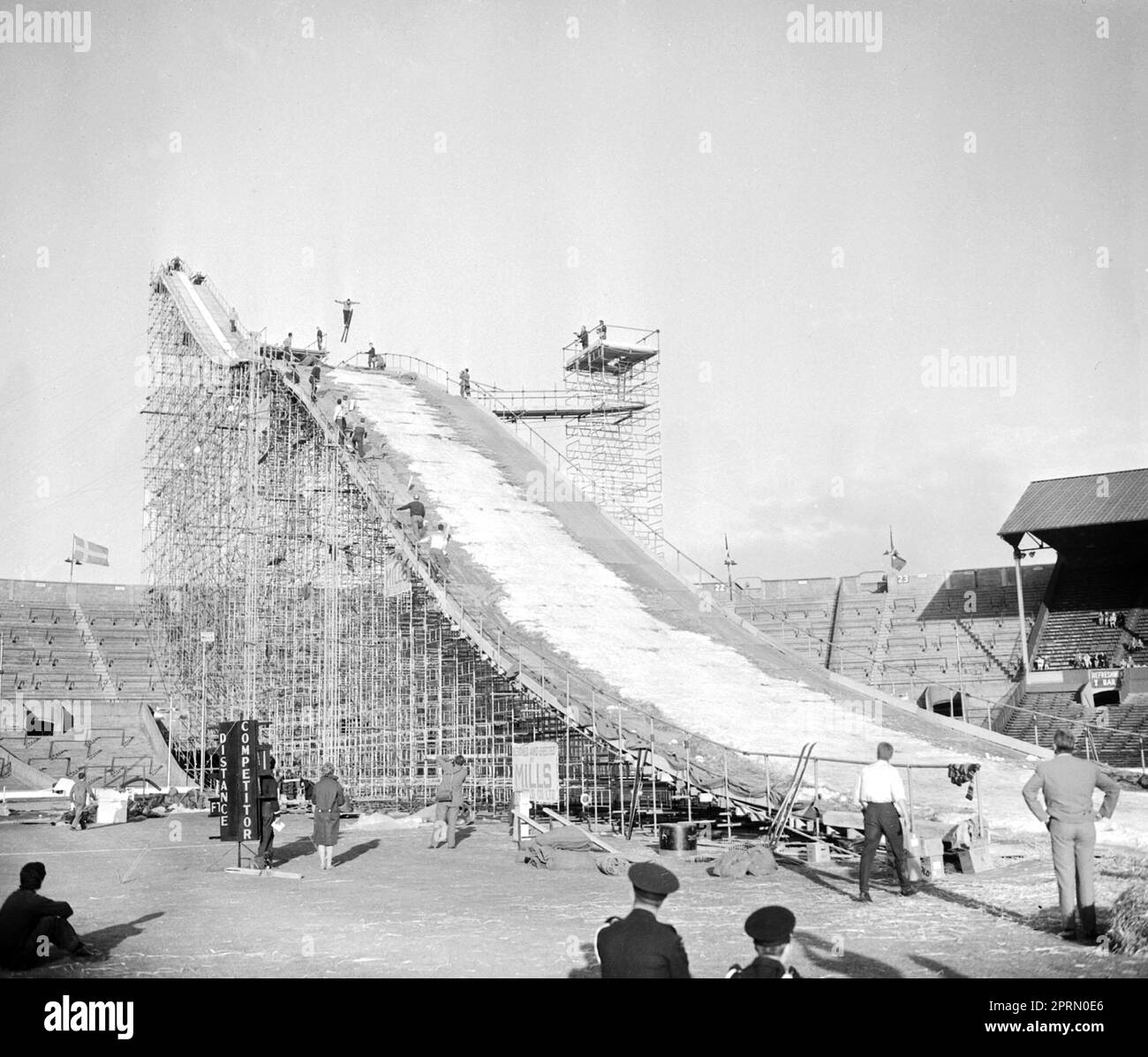 File photo dated 31-05-1961 of A mesh of scaffolding takes the place of the customary mountain slope as a skier soars through the air on the way down to an arena that's seen rodeos, cup finals and other spectacles but has not, until now, staged a ski jumping contest. Wembley was the unlikely venue for a Winter Sports Exhibition in the summer of 1961, with a mesh of scaffolding replacing the customary mountain for a ski jump. Issue date: Thursday April 27, 2023. Stock Photo