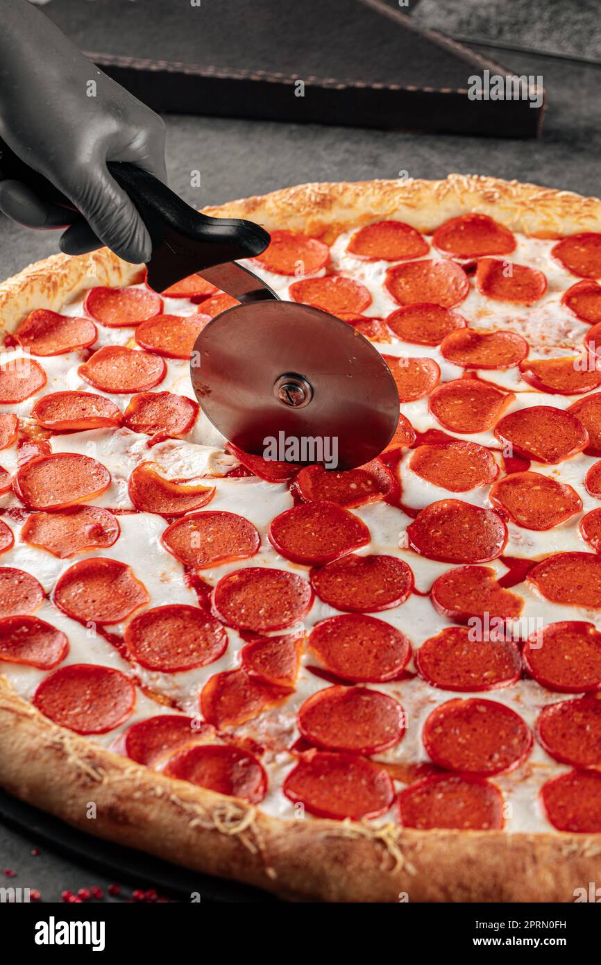 Cutting giant pepperoni pizza with special knife Stock Photo Alamy