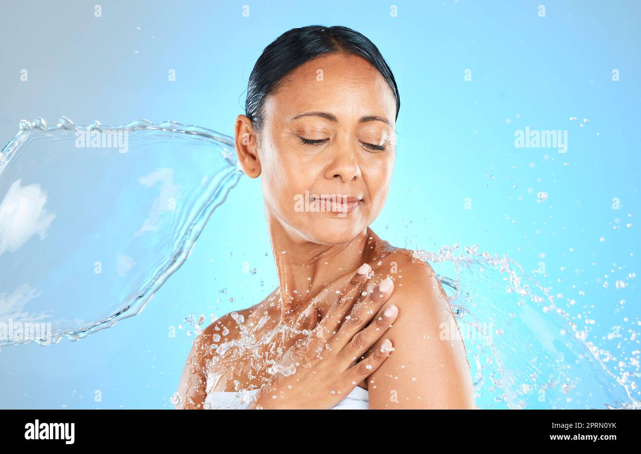 Beauty, skincare and splash with water and woman for shower, wellness or spa. Relax, refreshing or water with model against blue background for hydrat Stock Photo